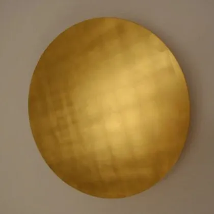Ein goldener Kreis an einer hellen Wand.